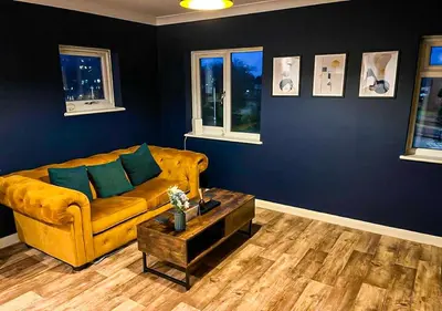 a living room with a yellow couch and blue walls at Stylish & Modern Apartment - Southend Stays in Southend-on-Sea