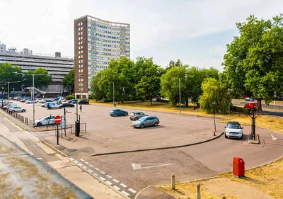 a parking lot with cars parked in front of a tall building at Stylish & Modern Apartment - Southend Stays in Southend-on-Sea