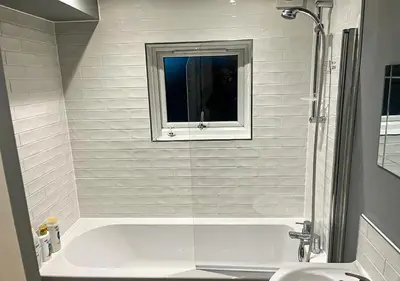 a white bath tub with a window in a bathroom at Stylish & Modern Apartment - Southend Stays in Southend-on-Sea