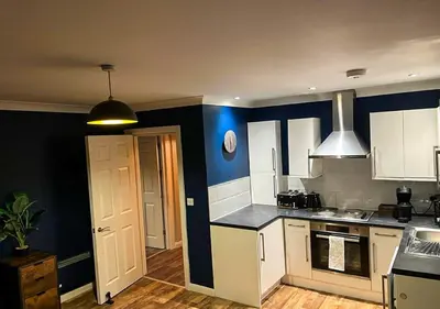 a kitchen with white cabinets and a blue wall at Stylish & Modern Apartment - Southend Stays in Southend-on-Sea