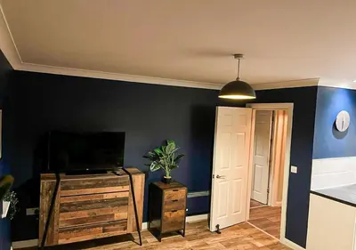 a living room with a tv and a blue wall at Stylish & Modern Apartment - Southend Stays in Southend-on-Sea