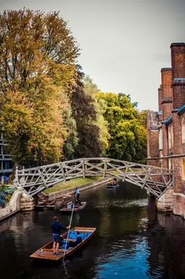 a man rowing two boats in a river under a bridge at Cosy Country Hideaway opposite Three Horseshoes Pub in Madingley village in Madingley