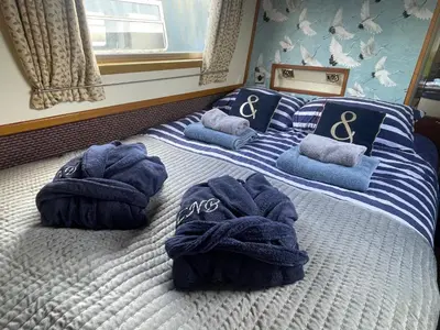 a bedroom with a bed with towels on it at Cambridge Narrowboats - Beautiful Narrowboat Glyndwr in Cambridge