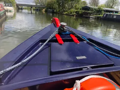 a blue boat with a rope on a river at Cambridge Narrowboats - Beautiful New Moon Narrowboat in Cambridge
