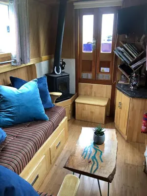 a living room with a couch and a wood stove at Cambridge Narrowboats - Beautiful New Moon Narrowboat in Cambridge