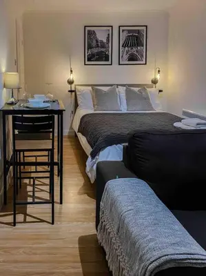 a bedroom with two beds and a table and a desk at Cozy studio near train station in Cambridge