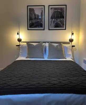 a bedroom with a large bed with three pictures on the wall at Cozy studio near train station in Cambridge