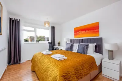 a bedroom with a large bed with a yellow blanket at 4 Bedroom House with Parking & Garden by Cherry Inn Short Let's & Services Accomodation in Cambridge