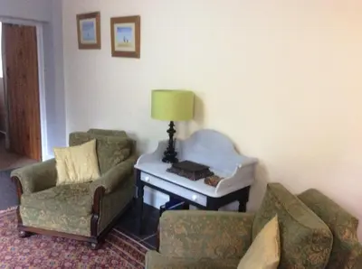 a living room with two chairs and a table with a lamp at The Old Pump House in Bungay