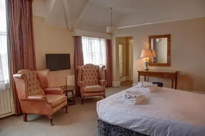 a hotel room with a bed and chairs and a television at The Orwell Hotel in Felixstowe