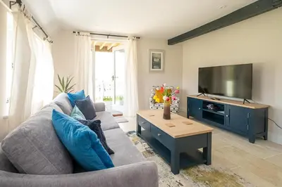 a living room with a couch and a flat screen tv at Boat Shelter Cottage in Thorpeness