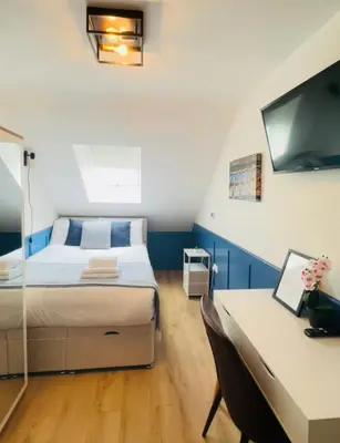 a bedroom with a bed and a desk and a tv at Sun Guest House Cambridge in Cambridge