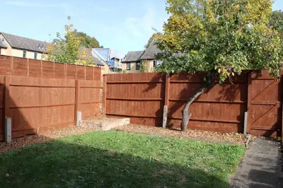 a wooden fence with a tree in a yard at A Comfortable Nest for Contractors or Families - sleeps 8 in Chesterton