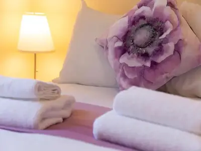 a room with a bed with towels and a flower on it at Pass the Keys Modern and Spacious Terrace in Central Cambridge in Cambridge