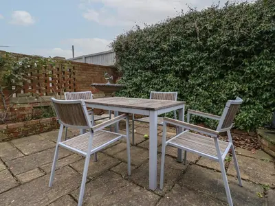 a table and two chairs sitting next to a hedge at 42 Crag Path in Aldeburgh