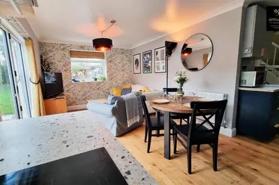 a living room with a table and a couch at The Rose Garden of Basildon in the Heart of Basildon by Artisan Stays I Weekly or Monthly Stay Offer I Pvt Parking I Sleeps 6 in Basildon