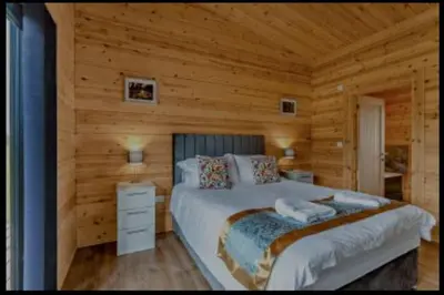 a bedroom with a bed in a log cabin at Meadow Valley Lodge 3 - Hot Tub in Hintlesham
