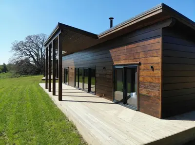 a building with a wooden deck next to a field at Meadow Valley Lodge 3 - Hot Tub in Hintlesham