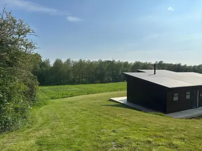 a small black building on a grassy field at Meadow Valley Lodge 3 - Hot Tub in Hintlesham
