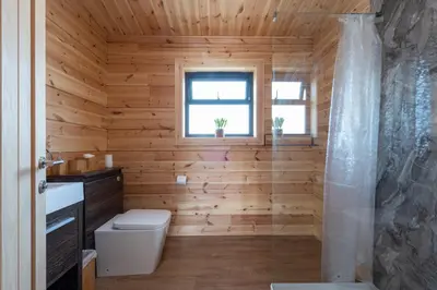 a wooden bathroom with a toilet and a window at Meadow Valley Lodge 3 - Hot Tub in Hintlesham