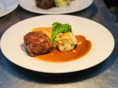 a plate of food with meat and broccoli on a table at Sheene Mill in Melbourn