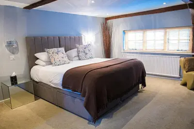 a bedroom with a large bed with a blue wall at Sheene Mill in Melbourn