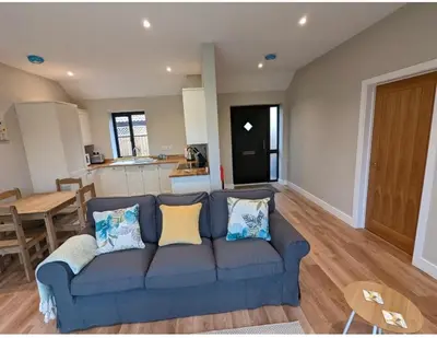 a living room with a blue couch and a kitchen at Meadow View Lodges in Bury Saint Edmunds