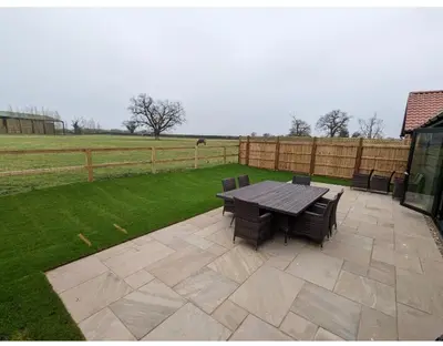 a patio with a table and chairs and a fence at Meadow View Lodges in Bury Saint Edmunds