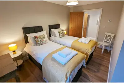 two beds in a small room with a table at Meadow View Lodges in Bury Saint Edmunds