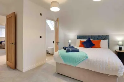 a bedroom with a large bed with orange and blue pillows at Kestrel Gardens Dunmow in Great Dunmow