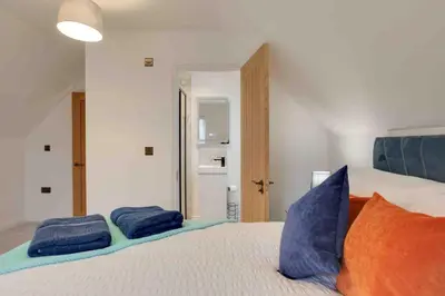 a bedroom with a bed with two blue pillows on it at Kestrel Gardens Dunmow in Great Dunmow