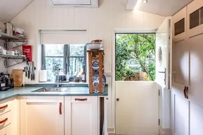 a kitchen with white cabinets and a sink and a window at The Little House, Orford in Woodbridge