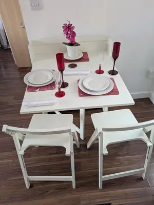 a white dining room table with two chairs and red wine glasses at Colchester Town, modern, detached, guest house in Colchester
