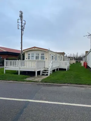 a white house with a porch and a white fence at Cosy Caravan near the beach in Walton-on-the-Naze