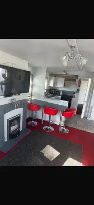 a kitchen with red chairs and a table and a fireplace at Cosy Caravan near the beach in Walton-on-the-Naze