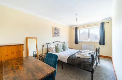 a bedroom with a bed and a table and a window at Spacious & Elegant 3BR Home Near Ipswich City Centre in Ipswich