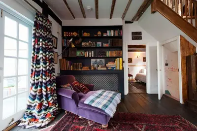 a living room with a purple couch and a book shelf at Charming Tudor riverside house in Wivenhoe