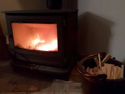 a fireplace with a fire in it next to a basket at Charming Tudor riverside house in Wivenhoe