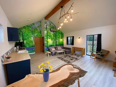 a large living room with a table and a kitchen at Bluebell Annexe in Little Grandsen