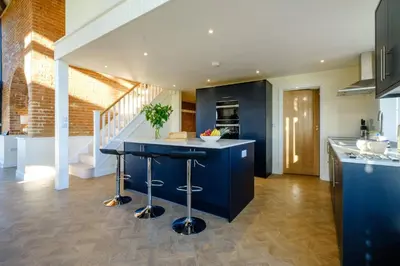 a kitchen with a blue island in the middle of a room at Upper Barn - a large family house by Aldeburgh Coastal Cottages in Ufford