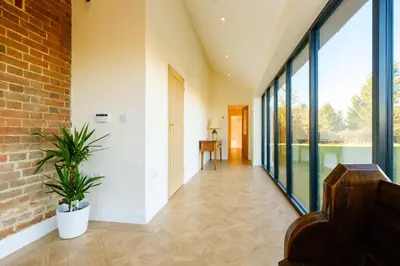 a hallway of a house with large glass windows at Upper Barn - a large family house by Aldeburgh Coastal Cottages in Ufford