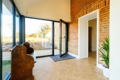 a hallway with glass doors and a brick wall at Upper Barn - a large family house by Aldeburgh Coastal Cottages in Ufford