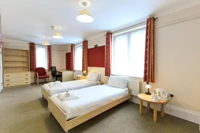 a hotel room with two beds and a desk at Selwyn College, Cambridge in Cambridge
