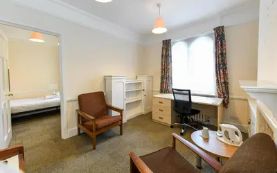 a living room with a desk and a bed at Selwyn College, Cambridge in Cambridge