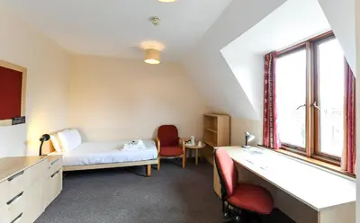 a room with a bed and a desk and a window at Selwyn College, Cambridge in Cambridge