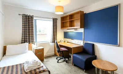 a room with a bed and a desk and a chair at Selwyn College, Cambridge in Cambridge
