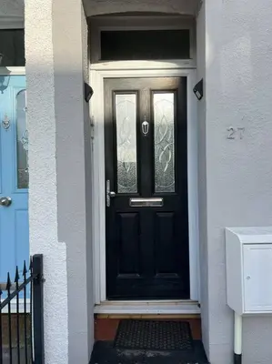 a black front door of a white house at Hill Grove 2 Bedroom Apartment in Leigh-on-Sea