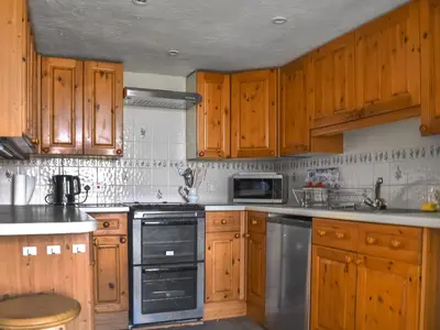 a kitchen with wooden cabinets and stainless steel appliances at Cherry Cottage in Ipswich