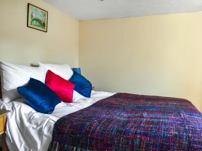 a bedroom with a bed with three pillows on it at Cherry Cottage in Ipswich