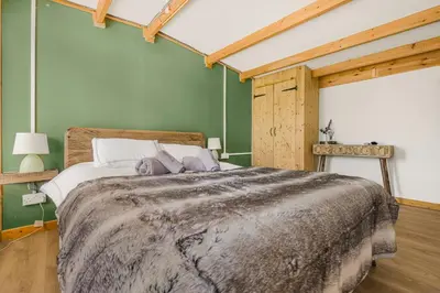 a bedroom with a large bed and a green wall at Cabin in the countryside in Sible Hedingham